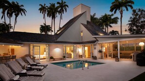 Ein modernes Haus mit Swimmingpool, Liegestühlen und einer Terrassenanlage.