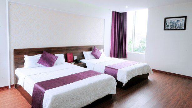 A hotel room with two beds, a wooden headboard, a window with curtains, and a framed picture on the wall. - Van Giang Hotel (Ninh Binh)