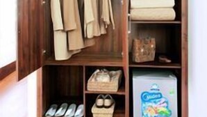 A wooden wardrobe with hanging clothes, folded linens, and storage boxes. - Van Giang Hotel (Ninh Binh)