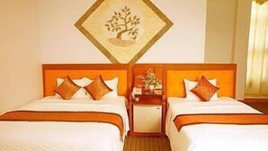 Hotelkamer met twee bedden, een houten hoofdbord, een nachtkastje en een schilderij van een boom aan de muur.