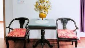 A room with a table and two chairs, an air conditioner, a framed picture, and a vase with flowers. - Van Giang Hotel (Ninh Binh)