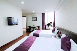 A hotel room with two beds, a television, a desk with a chair, and a window with curtains. - Van Giang Hotel (Ninh Binh)