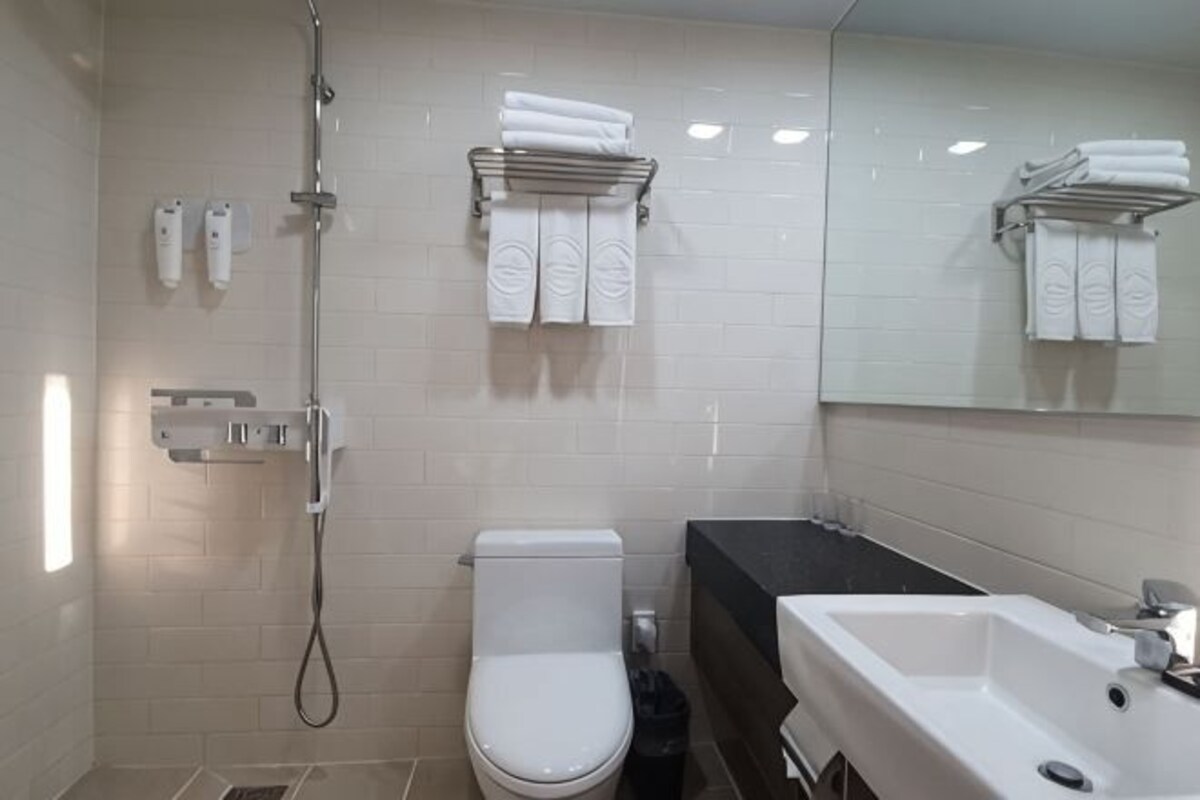 A bathroom with a toilet, a shower, a sink, and a towel rack.