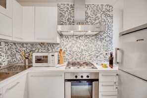 A modern kitchen with white cabinets, a microwave, a gas stove, and an oven. - GuestHost - Coverciano Modern Apartment with Patio! (Firenze)