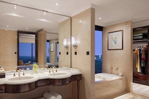 A luxurious bathroom with a large mirror, two sinks, and a view of the cityscape.