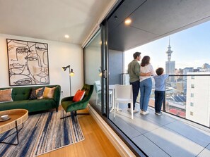 A modern living room with a green sofa, a floor lamp, and a large abstract painting. - Designed Penthouse 2Bed & 2Bath with SkyTower View on Queen St (Auckland)