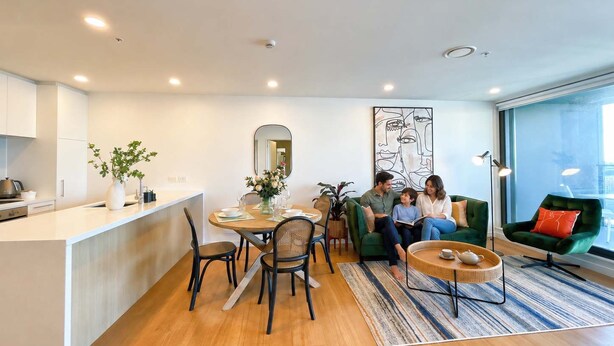 Um espaço de estar moderno com área de jantar, um sofá verde e uma janela ampla.