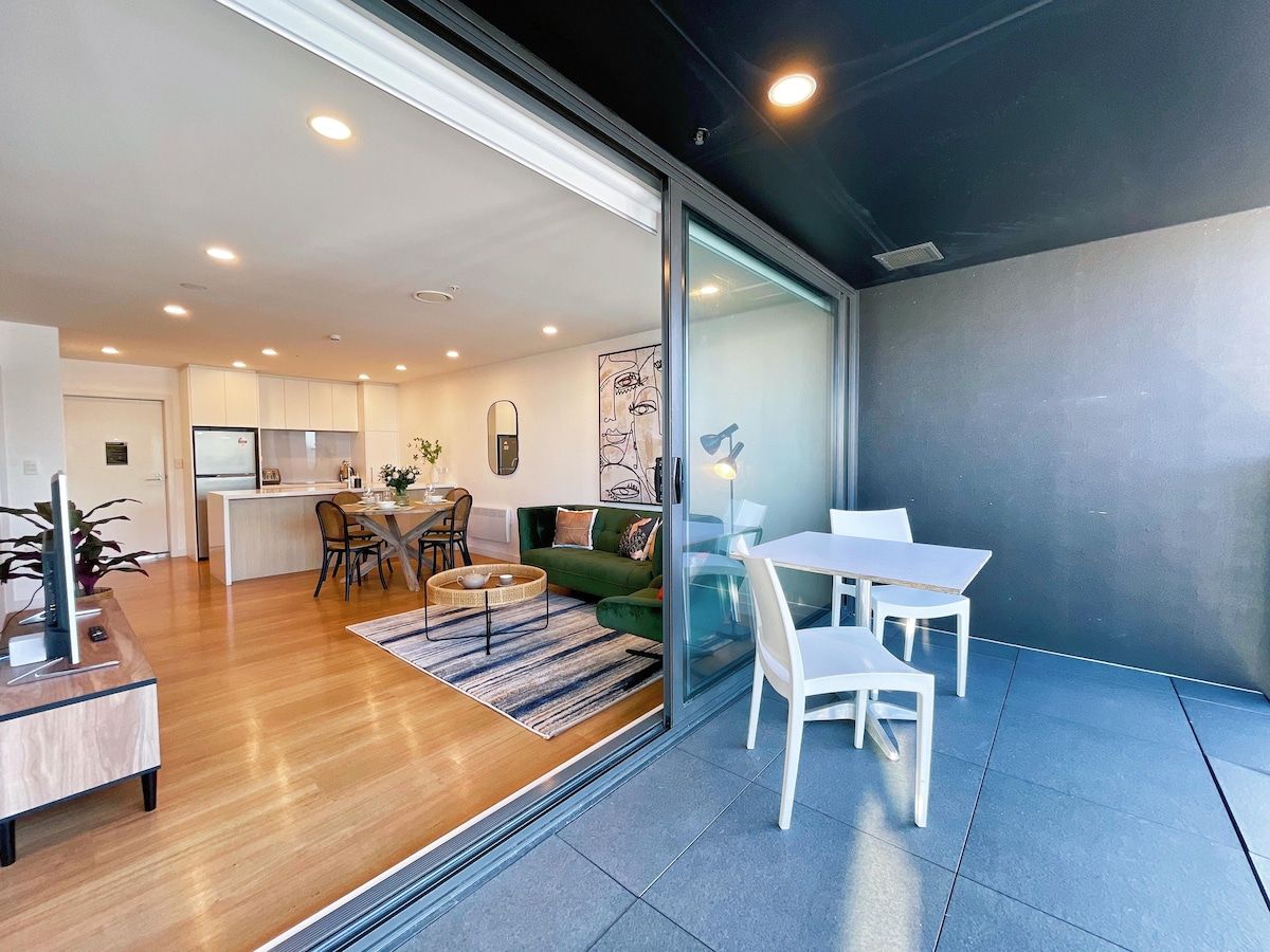A modern interior with a dining area, a sofa, and a kitchen in the background.