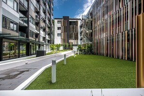 A modern building with multiple balconies, a paved walkway, and a well-maintained grassy area.
