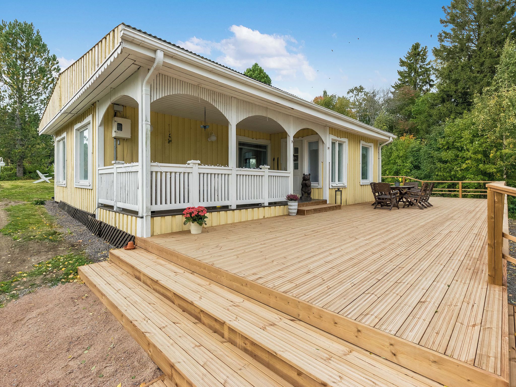 A wooden deck with a covered porch and a small outdoor seating area.