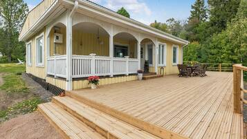A wooden deck with a covered porch and a small outdoor seating area.