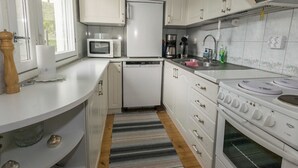 A compact kitchen with white cabinets, a microwave, a coffee maker, and a stove.