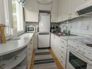 A compact kitchen with white cabinets, a microwave, a refrigerator, a coffee maker, and a stove.