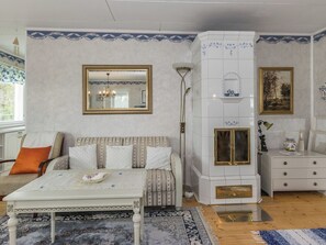 A room with a sofa, a table, a fireplace, a mirror, and a lamp.