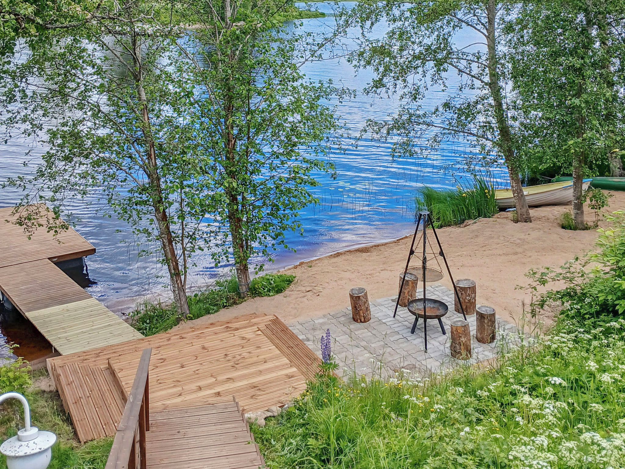 A lakeside outdoor area with a wooden deck, a swing set, and a fire pit.