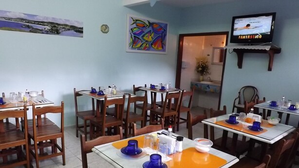 Un restaurant doté de nombreuses tables et chaises, d’un téléviseur fixé au mur et d’œuvres d’art accrochées aux murs.