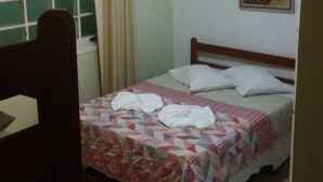 Une chambre à coucher avec un lit, une fenêtre avec des rideaux, un tableau au mur et une chaise.