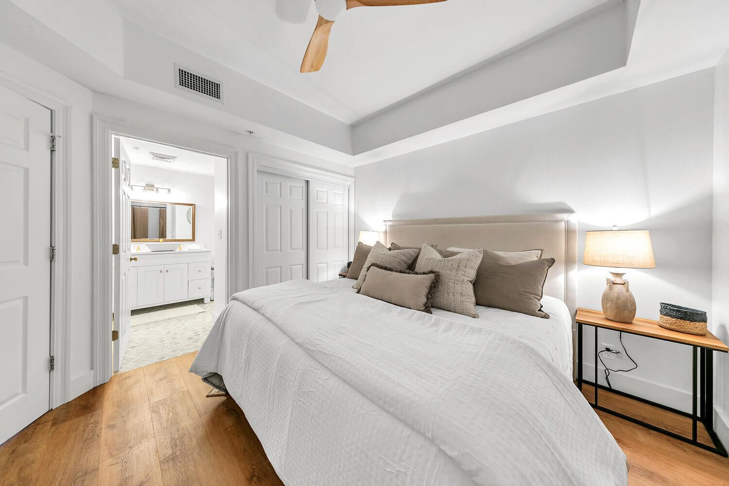A bedroom with a bed, a nightstand, a lamp, and a ceiling fan.