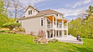 Ein zweigeschossiges Haus mit überdachter Veranda und einem angelegten Garten.