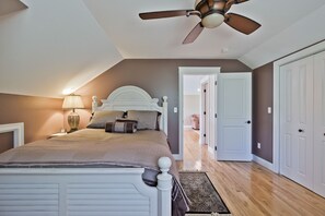 Une chambre à coucher avec un lit, un ventilateur de plafond, une table de chevet et une lampe.