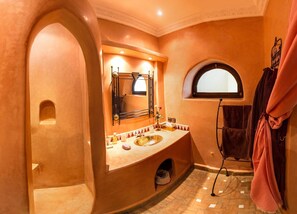 A bathroom with a curved vanity, a large mirror, a sink, and a towel rack.