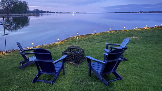 Two Adirondack chairs facing a calm lake with a distant shoreline and a clear sky. - A Fisherman’s and birdwatchers Paradise! (Carrying Place)