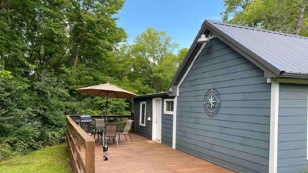 A deck with a grill and chairs, a covered area with an umbrella, and a compass on the building.