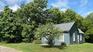 A single-story house with a sloped roof, surrounded by a well-maintained lawn and a large tree in front.