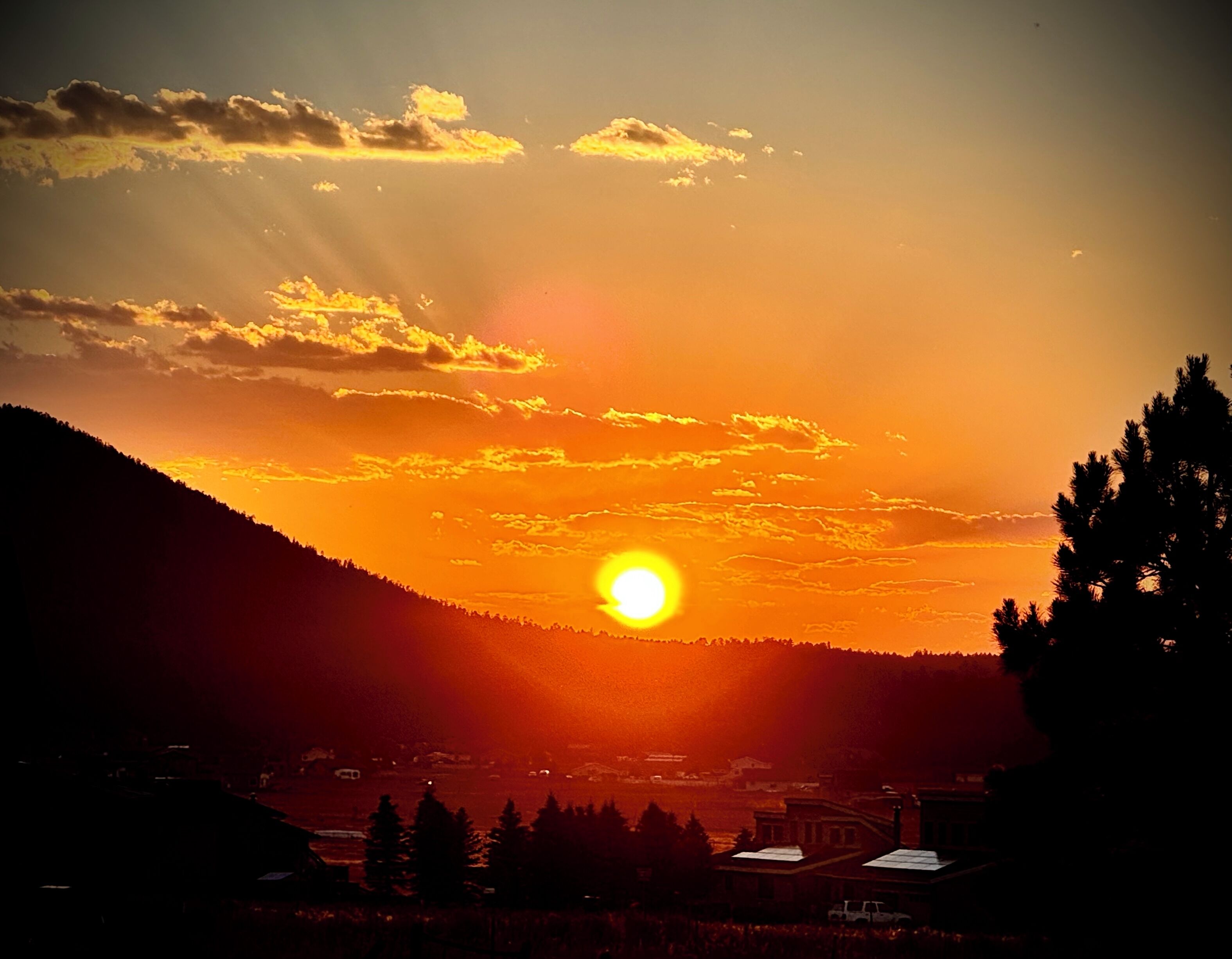 Un coucher de soleil sur un paysage montagneux, avec un village en contrebas.