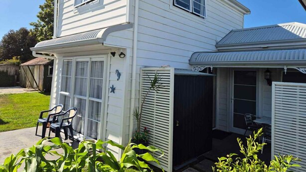 Ein zweistöckiges Haus mit überdachter Terrasse und Garage.