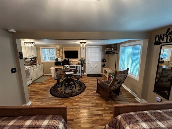 A compact kitchen with a dining area, a small seating space, and a window with blinds.