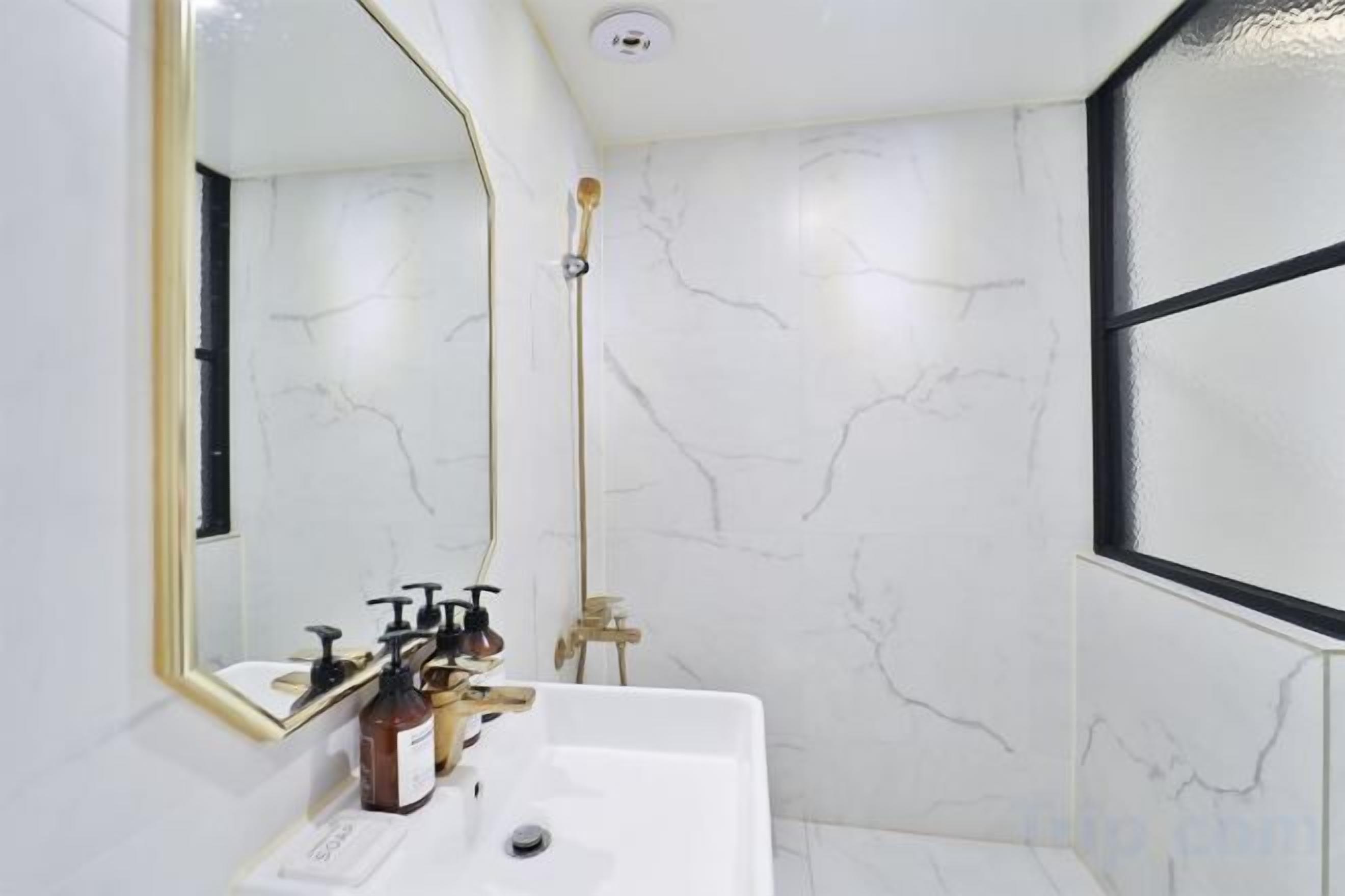 A bathroom with a white sink, a mirror with a gold frame, and a shower with a glass door.