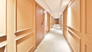 A long, narrow hotel corridor with wooden paneling on the walls and a tiled floor. - NO25 (Incheon)