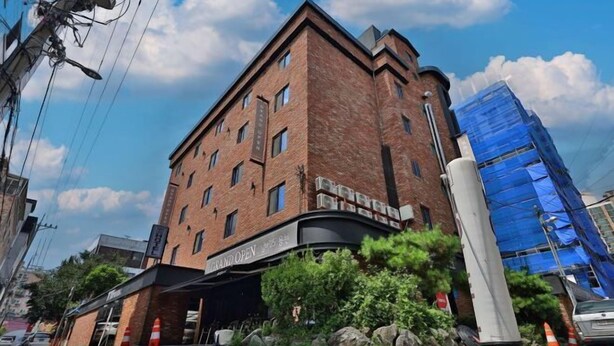 A multi-story brick building with a curved entrance and a sign indicating 'SWAND OPEN'. - NO25 (Incheon)