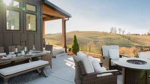 A covered outdoor patio with wicker furniture, a fire pit, and a scenic view of rolling hills. - Cottage with panoramic hilltop views and stocked pond on 80 acres.  (Spring Hill)