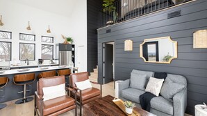A modern kitchen with a bar area, a grey sofa, and a wooden coffee table. - Cottage with panoramic hilltop views and stocked pond on 80 acres.  (Spring Hill)