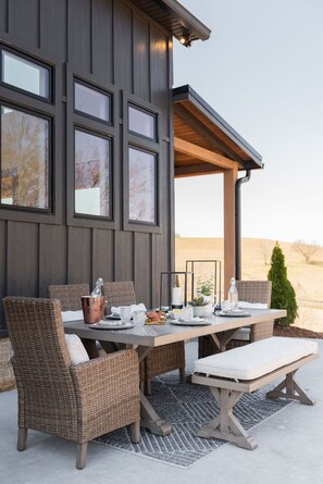 Un área de comedor al aire libre con muebles de mimbre, una mesa para dos personas y vistas del paisaje.