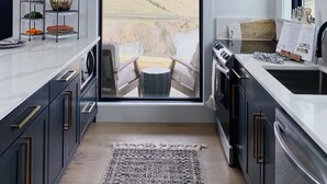 A modern kitchen with a large window, a clock, and a view of a landscape. - Cottage with panoramic hilltop views and stocked pond on 80 acres.  (Spring Hill)
