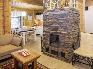 A cozy cabin interior with a stone fireplace, wooden furniture, and a dining area.