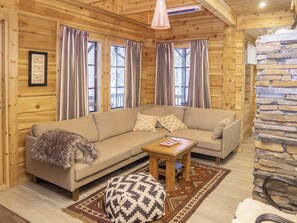 L’intérieur d’un chalet confortable, avec un canapé, une petite table en bois et un pouf à motifs.