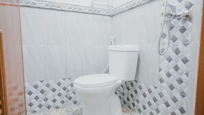 Une salle de bain avec des toilettes, une douche et des carreaux décorés.
