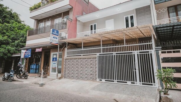 Un immeuble à plusieurs étages doté d’une entrée sécurisée par un portail, d’un distributeur automatique de billets bien visible et d’un balcon avec une balustrade.