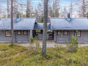 A log cabin with a porch and chimney, surrounded by trees.