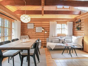 Ein Holzblockhaus-Interieur mit Essbereich, Sofa und einem großen Fenster.