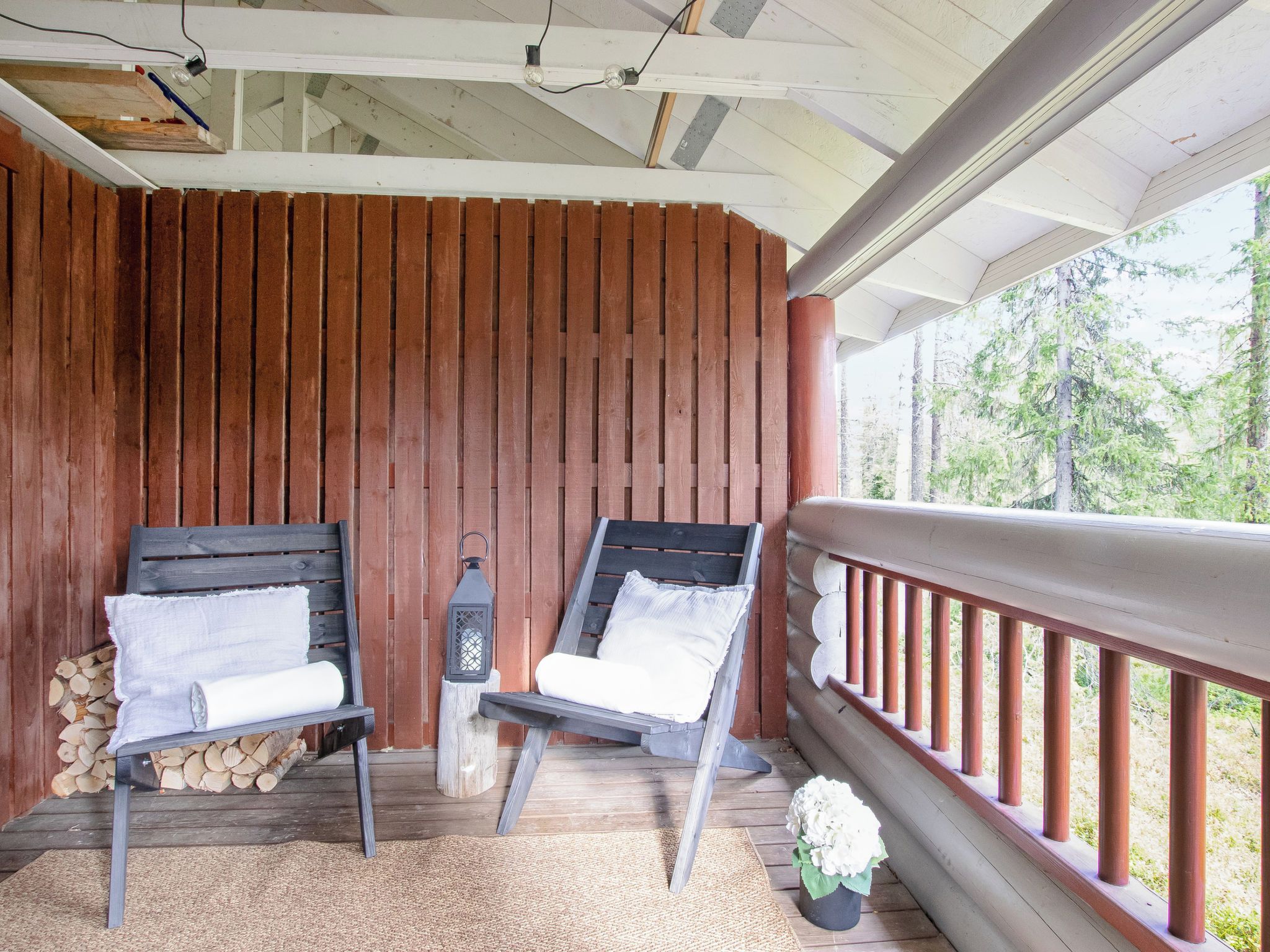 A wooden deck with two chairs, a lantern, and a railing.