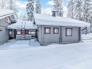 A log cabin with a snow-covered roof and a wooden porch.
