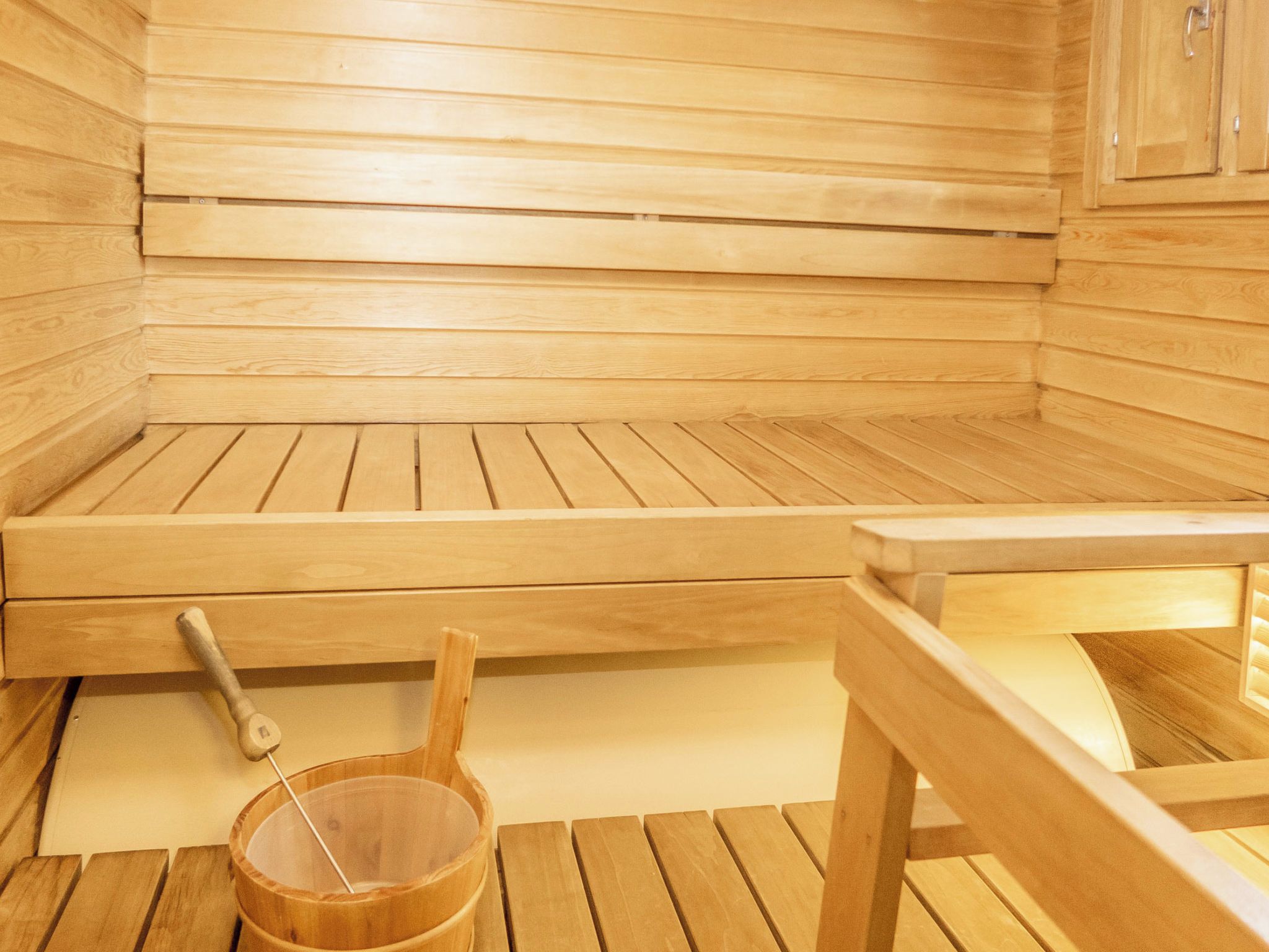 Et sauna rum med træbænke og en trætønde.