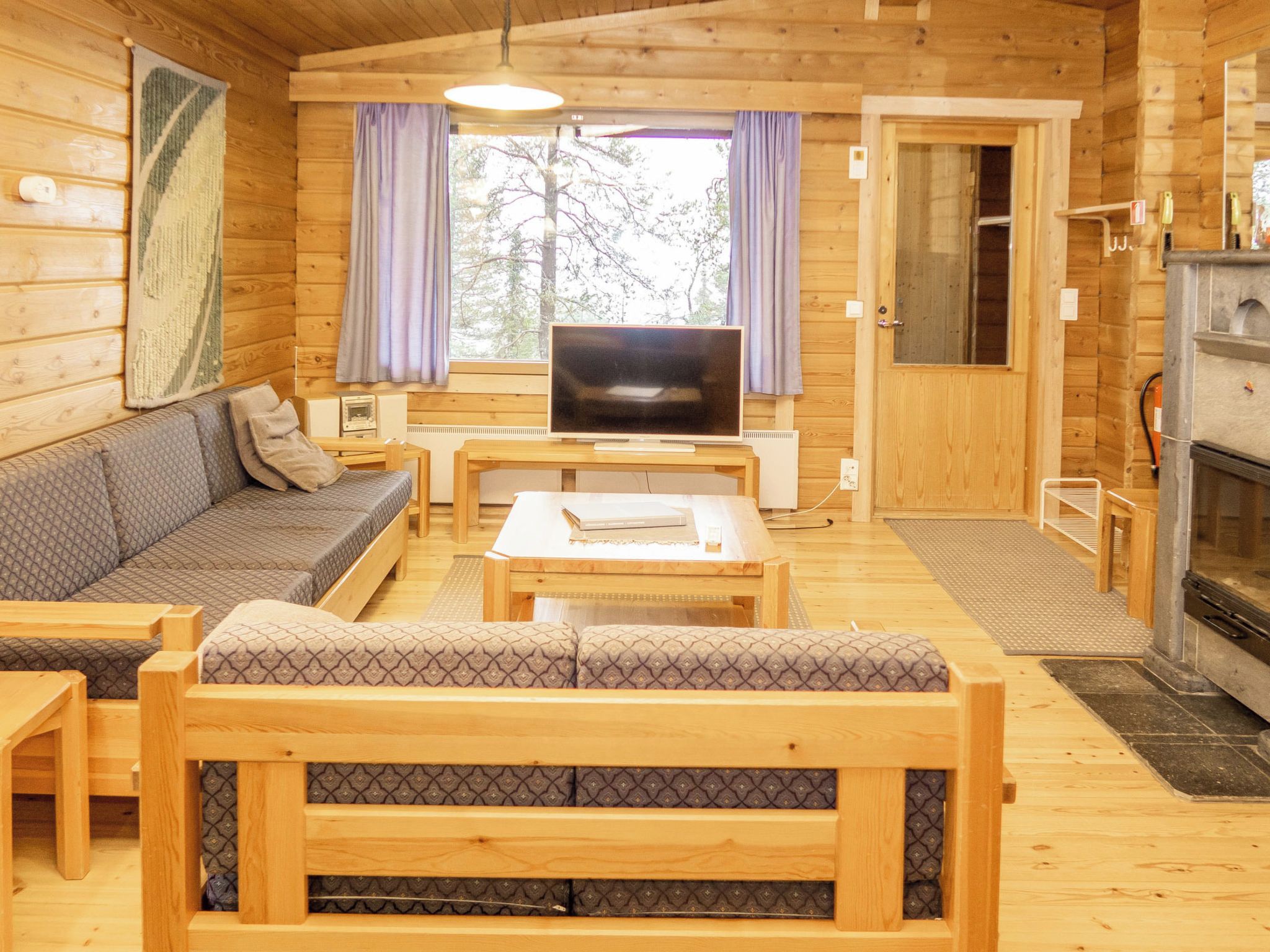 L’intérieur d’un chalet accueillant, avec un canapé, un téléviseur et une cheminée.