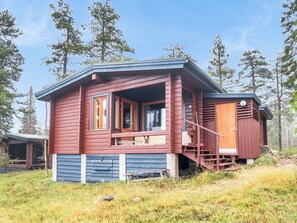 A cabin with a porch, a staircase, and a door with a number.