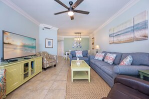 A living room with a television, sofa, coffee table, and patterned armchair. - Three Bedroom ~ Gulf Front ~ Pelican Pointe! (Orange Beach)